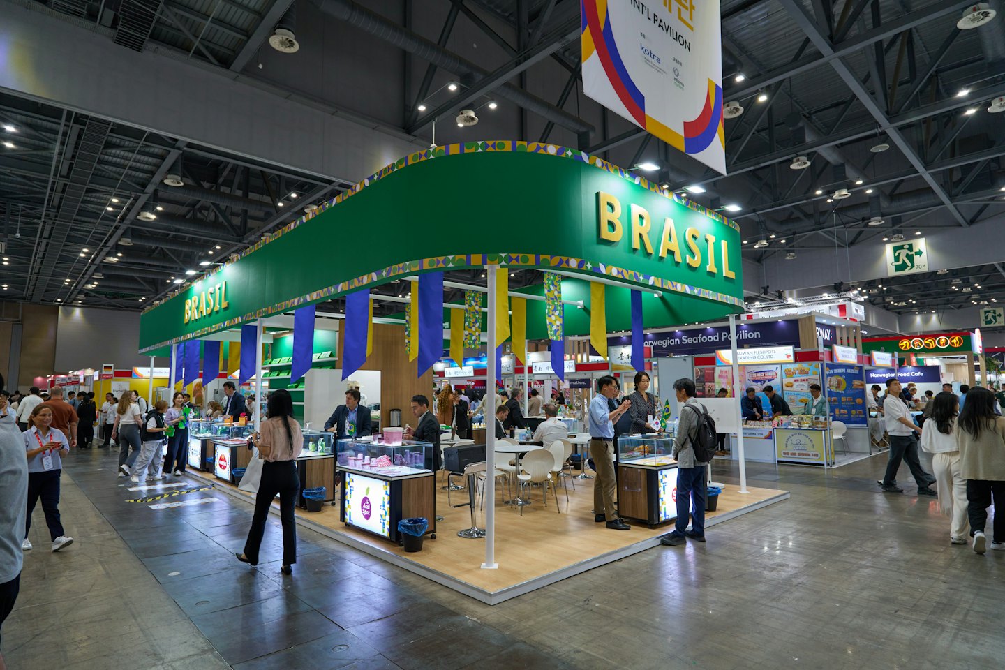 Asistentes caminan por un concurrido salón de exposiciones lleno de stands.