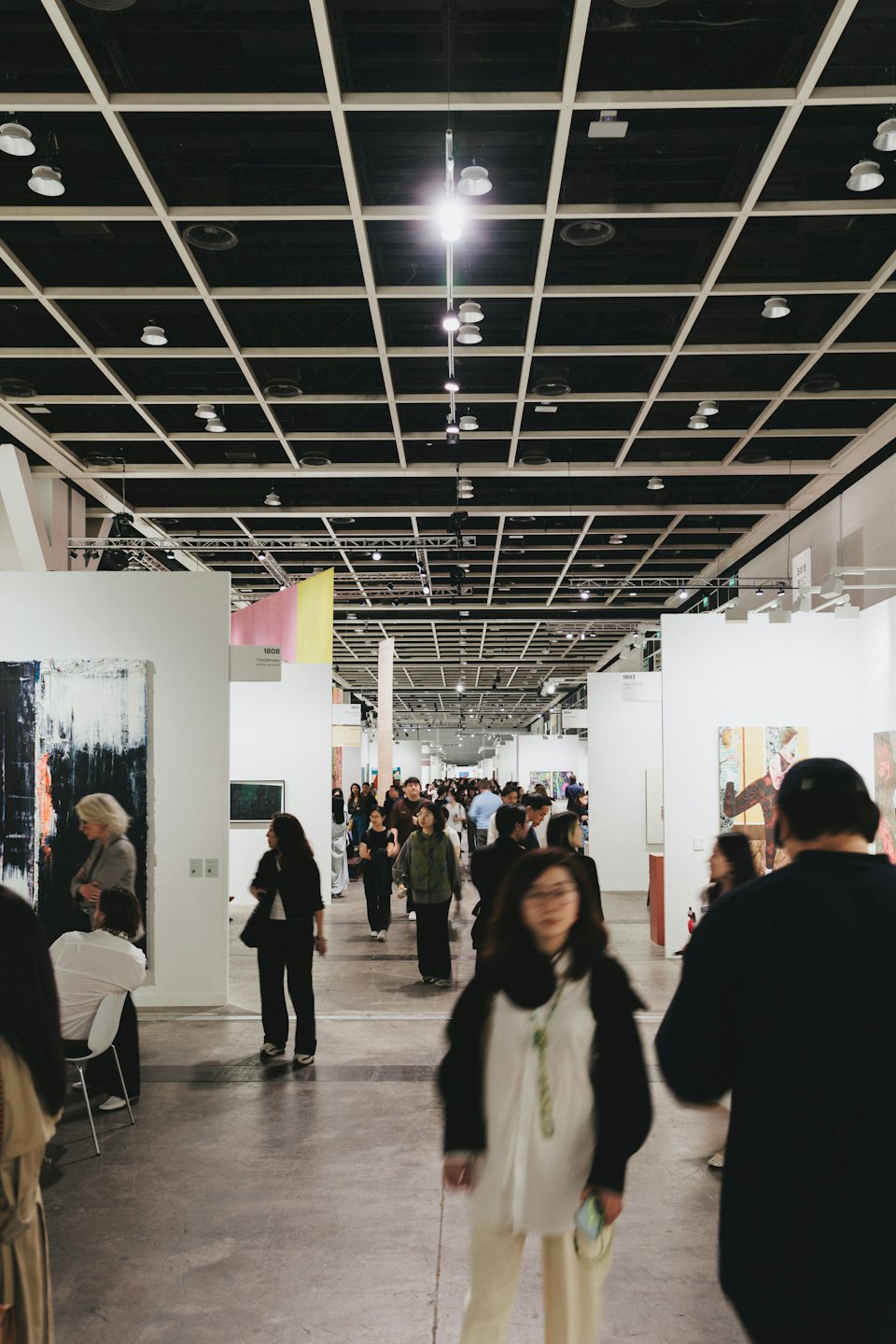 Gente explorando arte abstracto en una exposición interior.