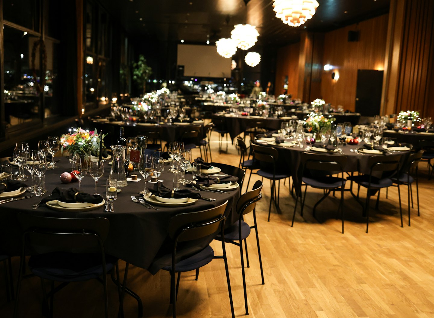 Mesas de evento formales con cubiertos y centros de mesa florales.