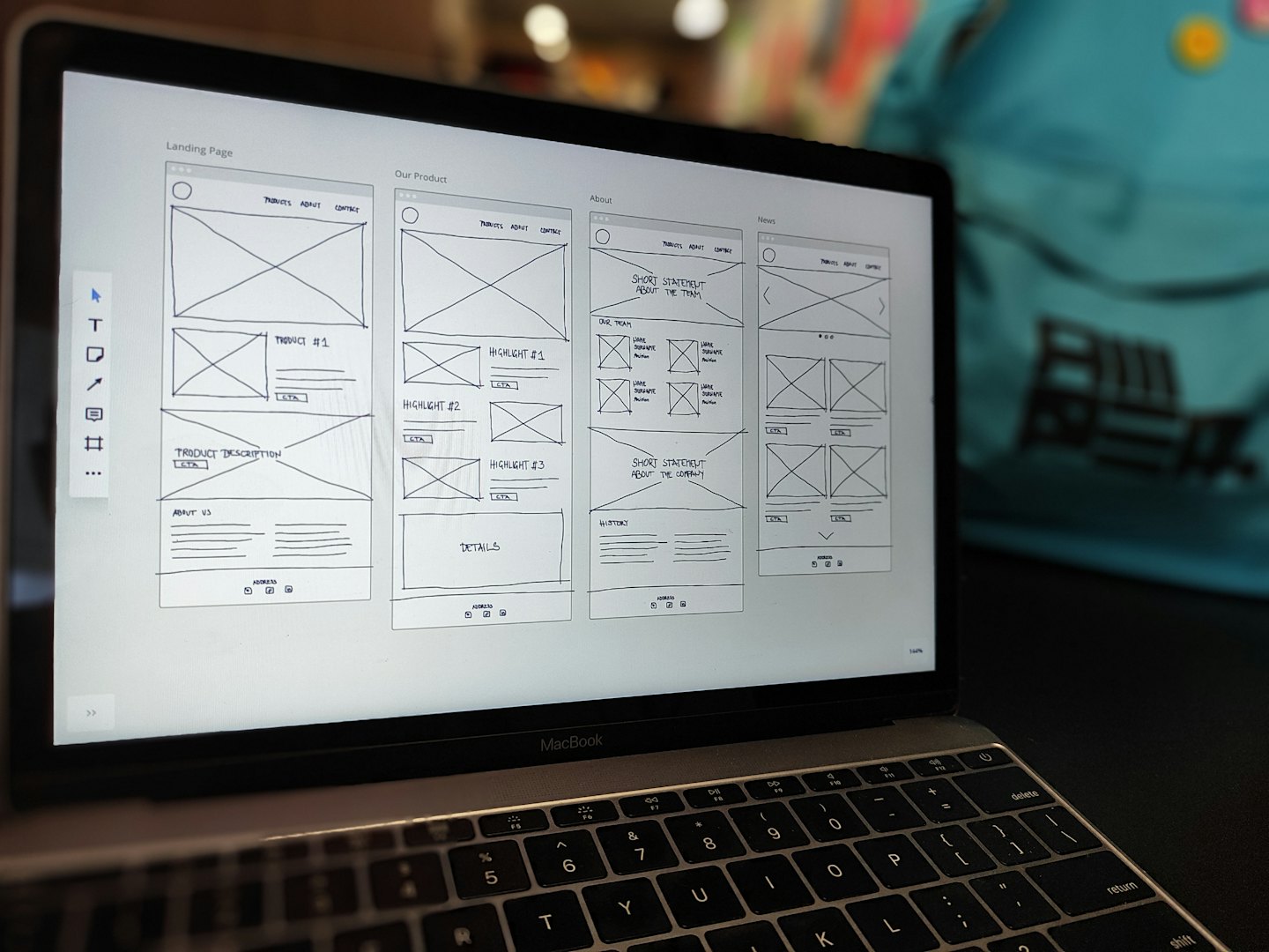 La pantalla de un portátil muestra bocetos en blanco y negro para el diseño de un sitio web.