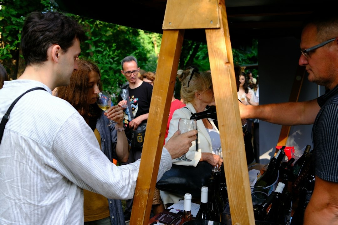 People enjoy wine tasting at a rustic outdoor stand.